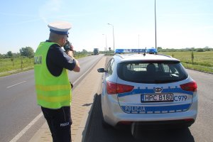 zdjęcie przedstawia policjanta ruchu drogowego mierzącego prędkość pojazdów