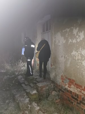 Policjant z pracownikiem socjalnym kontrolują miejsce, gdzie przebywają osoby bezdomne